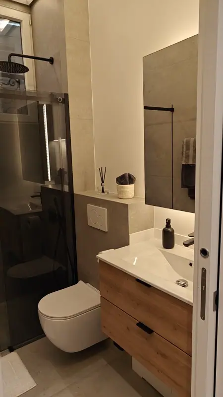 Salle d’eau avec douche vitrée et meuble vasque en bois