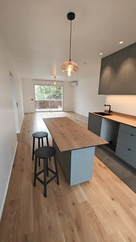 Cuisine ouverte avec îlot en bois et suspension, parquet en chêne