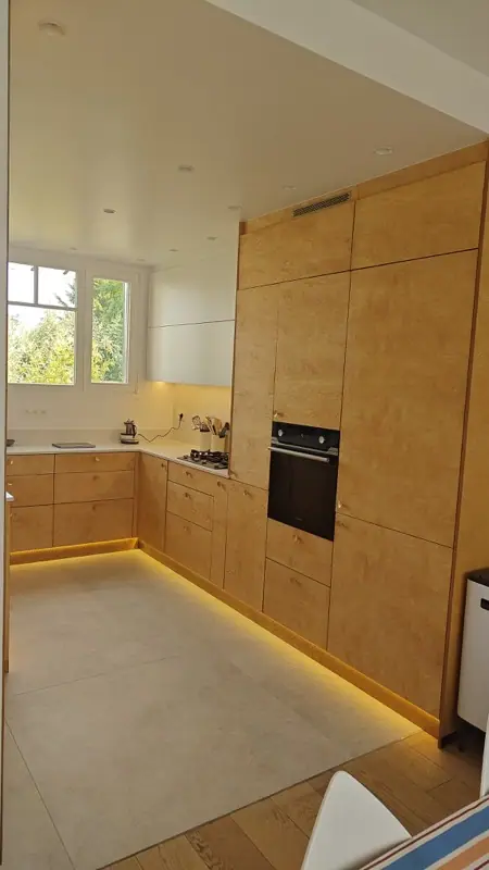 Cuisine en L aux façades en bois avec éclairage LED en plinthe