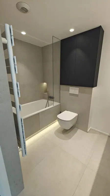 Salle de bains avec baignoire, radiateur sèche-serviettes et éclairage LED