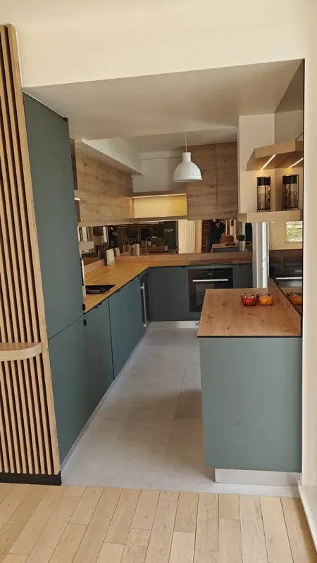 Cuisine ouverte aux façades vert sauge et plan de travail en bois