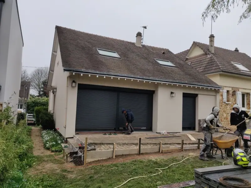 Dalle béton coulée devant une maison, équipe sur le chantier