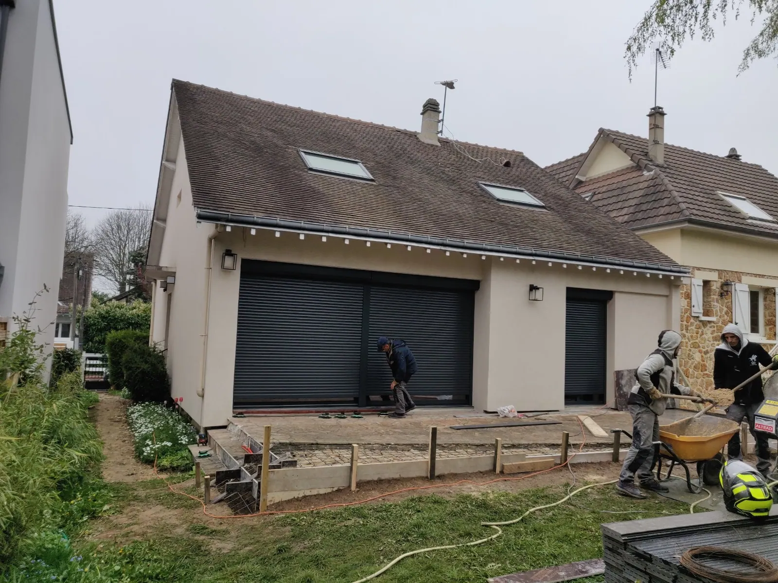 Dalle béton coulée devant une maison, équipe sur le chantier