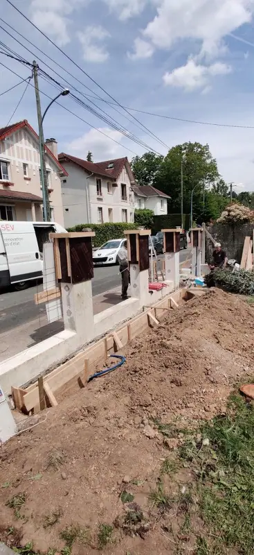 Fondations et coffrages des poteaux d’un muret le long de la rue
